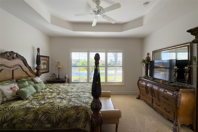 bedroom with ceiling fan, a raised ceiling, and light carpet