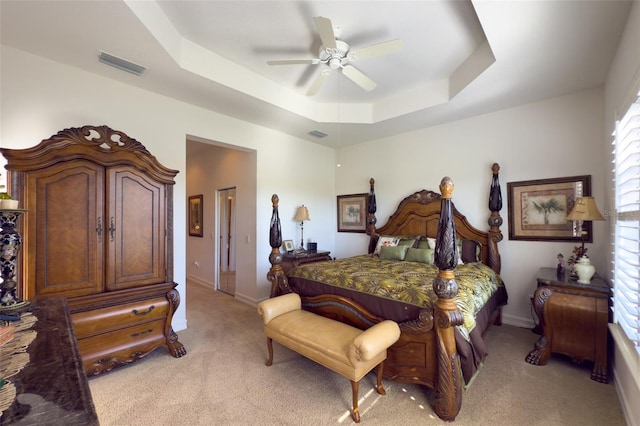 carpeted bedroom featuring a tray ceiling and ceiling fan