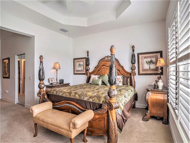 carpeted bedroom with a raised ceiling and ceiling fan