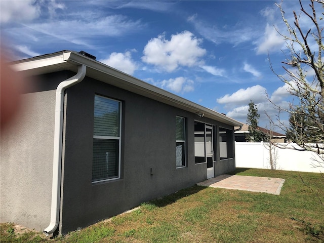 view of side of property with a patio and a lawn