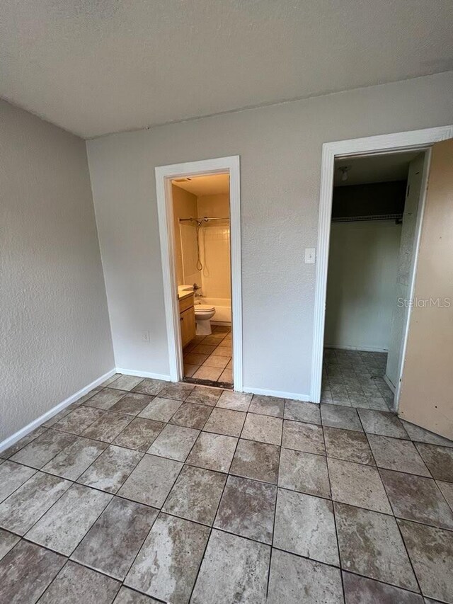 unfurnished bedroom with a walk in closet, ensuite bath, and a closet