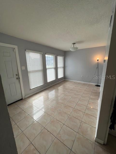 tiled empty room featuring a textured ceiling