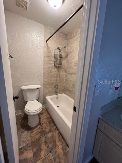 full bathroom with vanity, tiled shower / bath combo, and toilet