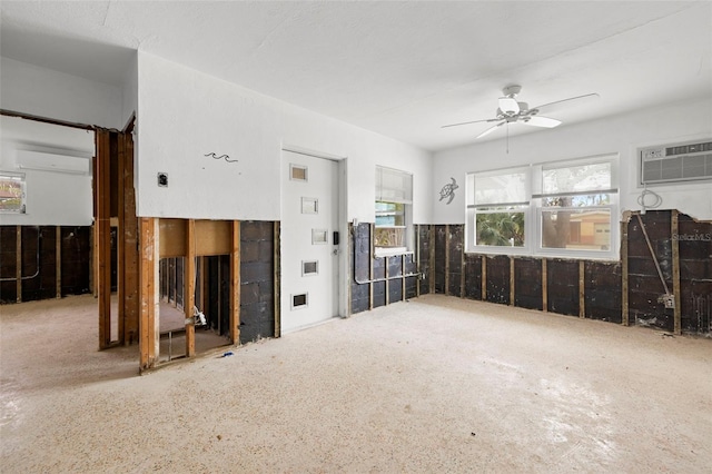 unfurnished living room featuring a wall mounted air conditioner and ceiling fan