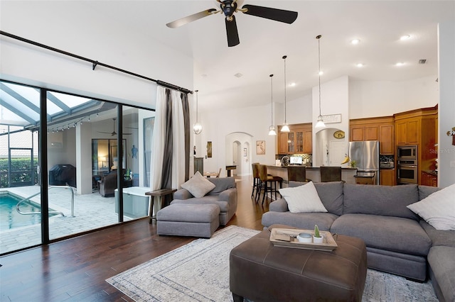 living room featuring a high ceiling, ceiling fan, and dark hardwood / wood-style floors