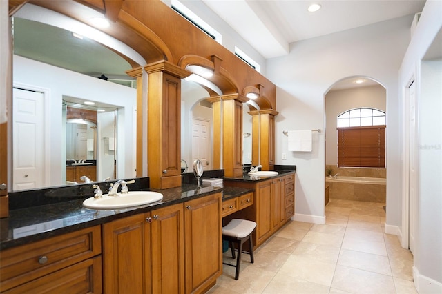 bathroom featuring a relaxing tiled tub, tile patterned floors, decorative columns, and vanity