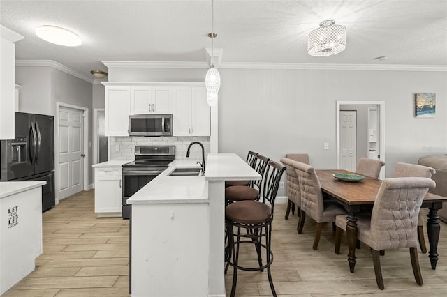 3611 19th St N, Saint Petersburg, FL 33713 - kitchen featuring stainless steel appliances, a sink, a textured ceiling, a kitchen breakfast bar, and light wood-type flooring