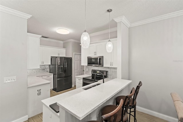 3611 19th St N, Saint Petersburg, FL 33713 - kitchen with appliances with stainless steel finishes, a breakfast bar area, backsplash, light wood-type flooring, and a textured ceiling