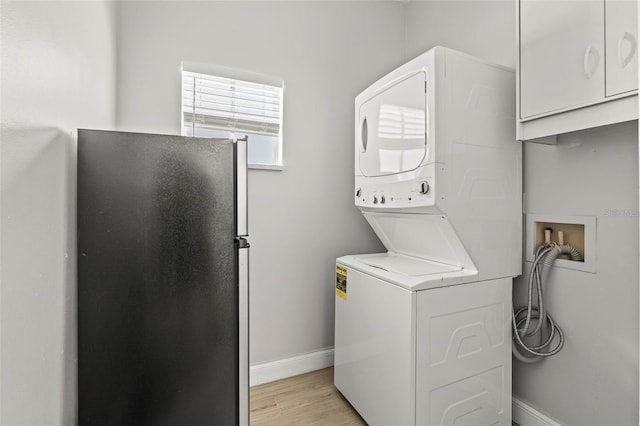 3611 19th St N, Saint Petersburg, FL 33713 - laundry area with stacked washer and clothes dryer, baseboards, light wood-style flooring, and cabinet space