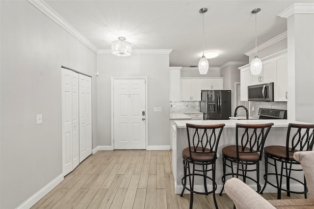 3611 19th St N, Saint Petersburg, FL 33713 - kitchen with appliances with stainless steel finishes, light countertops, a breakfast bar, backsplash, and light wood-style flooring