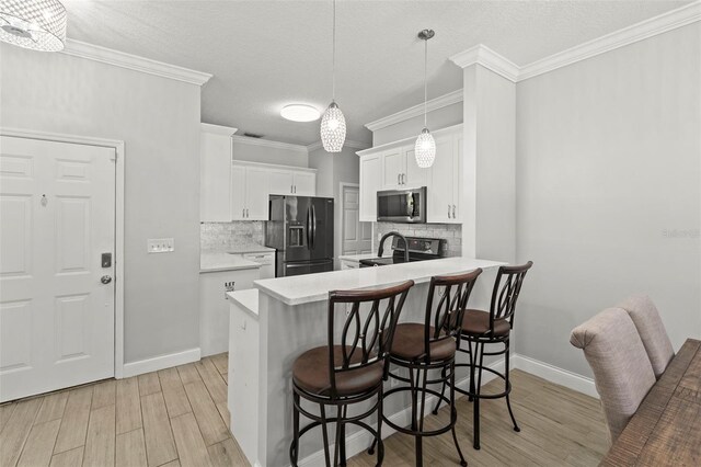 3611 19th St N, Saint Petersburg, FL 33713 - kitchen with stainless steel appliances, a breakfast bar, a peninsula, light wood finished floors, and backsplash
