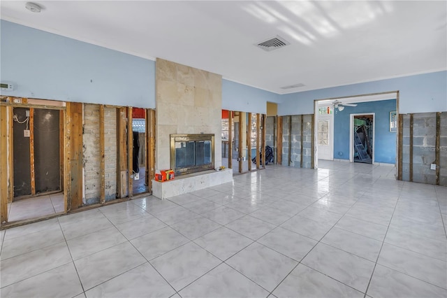 unfurnished living room with ceiling fan and a tile fireplace