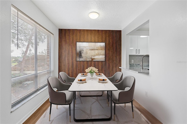 dining area with sink, a textured ceiling, and light wood-type flooring