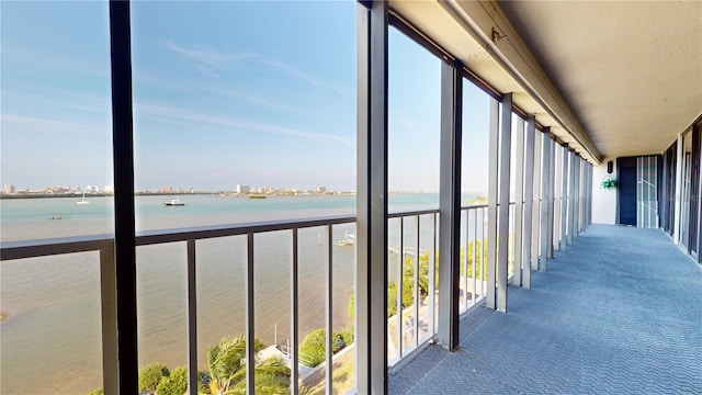 unfurnished sunroom featuring a view of the beach and a water view