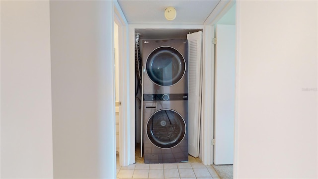 laundry area with light tile patterned floors and stacked washer and clothes dryer