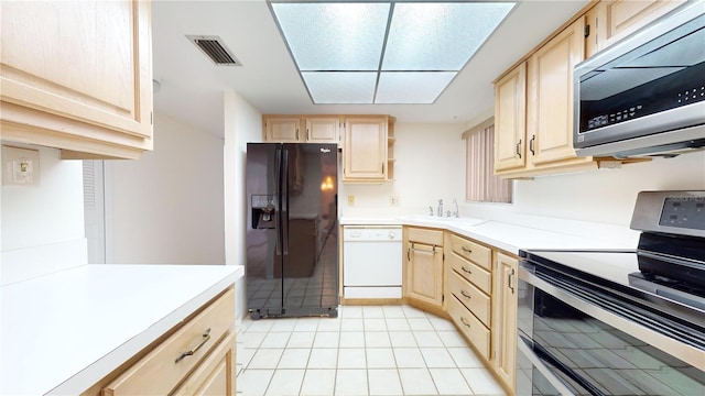 kitchen with appliances with stainless steel finishes, light brown cabinets, light tile patterned floors, and sink