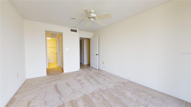 unfurnished bedroom with light carpet, ensuite bathroom, and ceiling fan