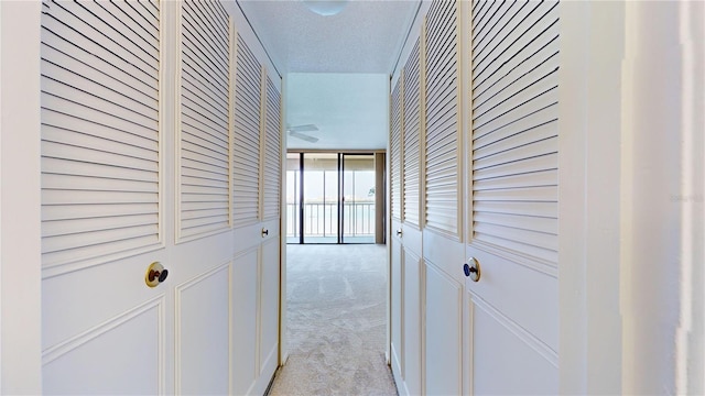 hallway with light carpet and a textured ceiling