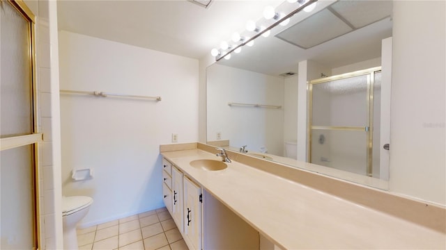 bathroom featuring tile patterned flooring, vanity, a shower with door, and toilet