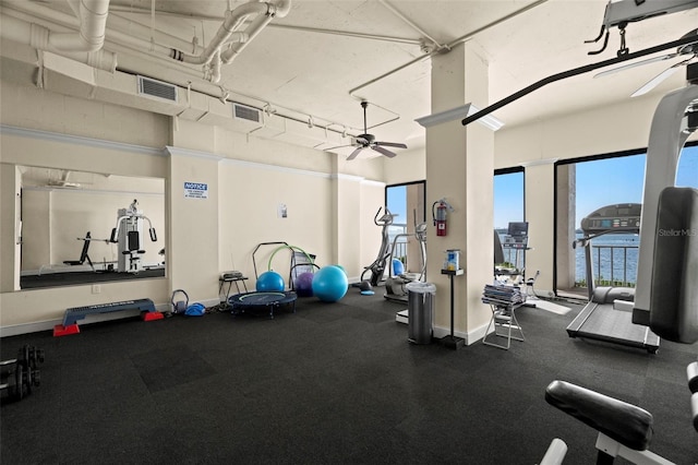 exercise room featuring ceiling fan, a water view, and a high ceiling