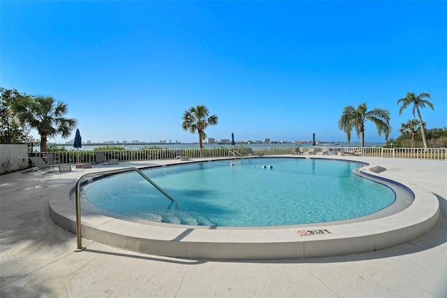 view of pool featuring a water view and a patio