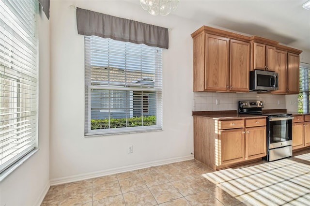 kitchen with light tile patterned flooring, appliances with stainless steel finishes, and tasteful backsplash