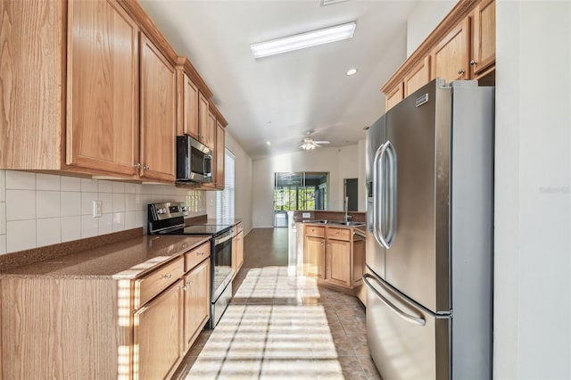 kitchen featuring kitchen peninsula, appliances with stainless steel finishes, tasteful backsplash, vaulted ceiling, and ceiling fan