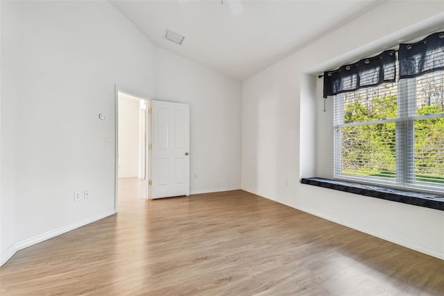 spare room with light hardwood / wood-style flooring and lofted ceiling