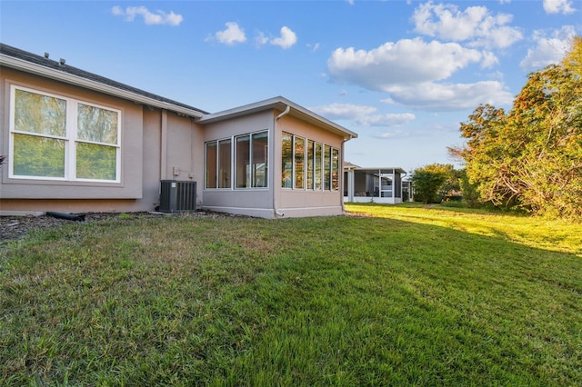 back of house with a yard, central air condition unit, and a sunroom