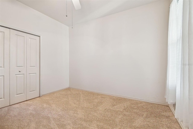 unfurnished bedroom with a closet, ceiling fan, and light colored carpet