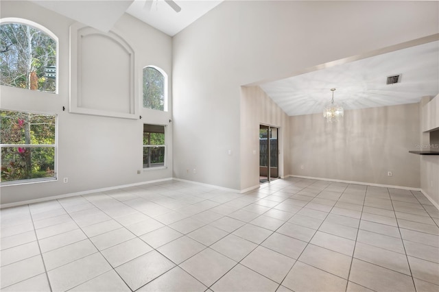 unfurnished living room with light tile patterned floors, ceiling fan with notable chandelier, and high vaulted ceiling