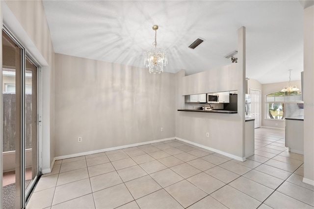 kitchen featuring lofted ceiling, light tile patterned flooring, a chandelier, and decorative light fixtures