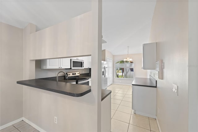 kitchen featuring lofted ceiling, white cabinets, hanging light fixtures, light tile patterned floors, and appliances with stainless steel finishes