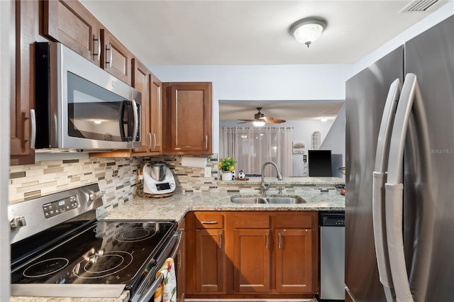 kitchen with light stone countertops, sink, stainless steel appliances, and tasteful backsplash