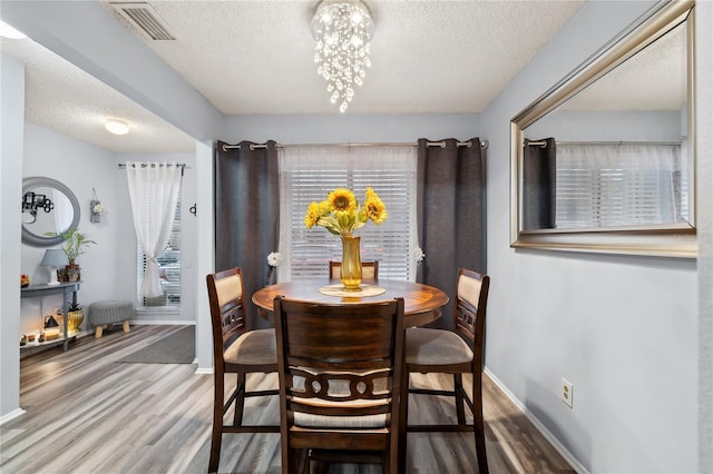 dining space with a textured ceiling, a chandelier, and hardwood / wood-style flooring