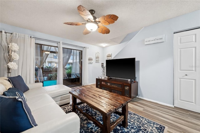 living room featuring a textured ceiling, ceiling fan, and wood-type flooring