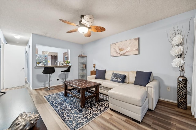 living room with wood-type flooring, a textured ceiling, and ceiling fan