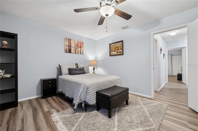 bedroom with ceiling fan, a textured ceiling, and wood-type flooring