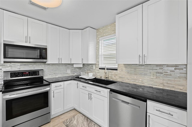 kitchen featuring sink, stainless steel appliances, tasteful backsplash, light hardwood / wood-style floors, and white cabinets