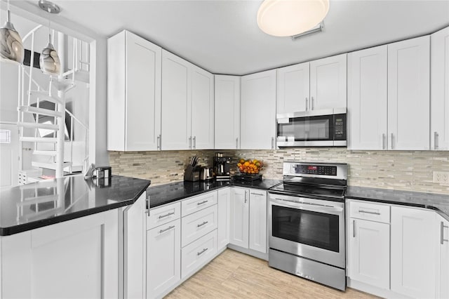 kitchen with white cabinets, light wood-type flooring, tasteful backsplash, decorative light fixtures, and stainless steel appliances