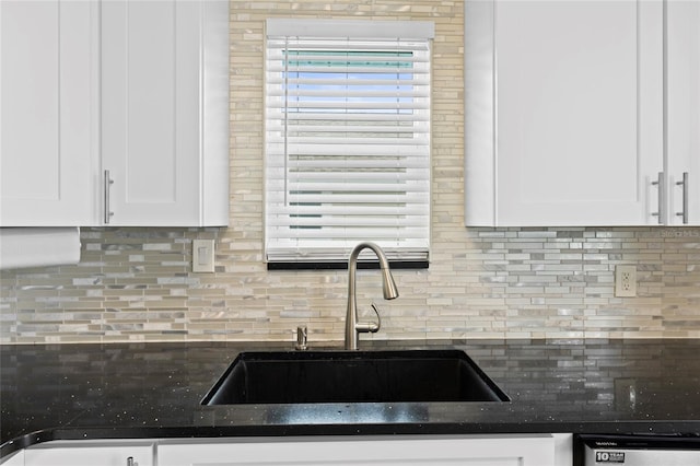 kitchen featuring stainless steel dishwasher, white cabinetry, sink, and tasteful backsplash