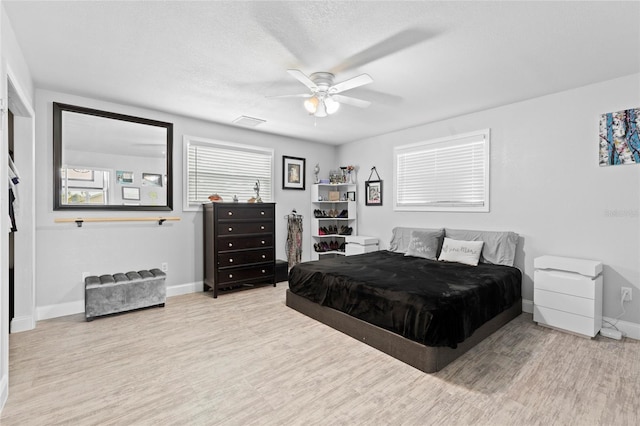 bedroom with ceiling fan, a textured ceiling, and light hardwood / wood-style flooring