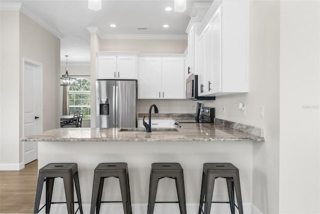 kitchen with sink, light stone countertops, appliances with stainless steel finishes, white cabinetry, and a chandelier