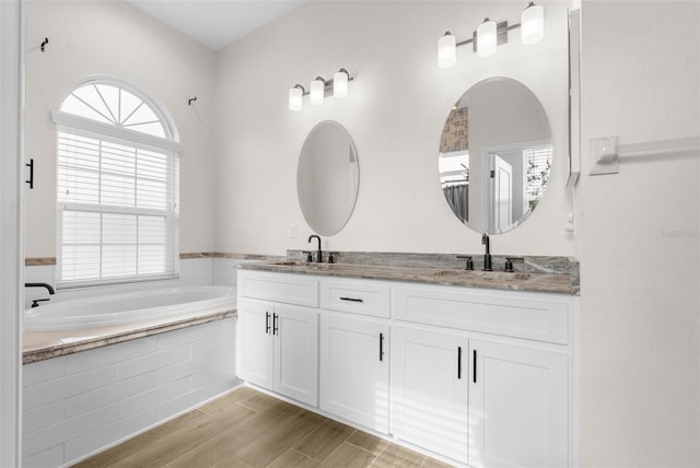 bathroom with vanity and tiled tub