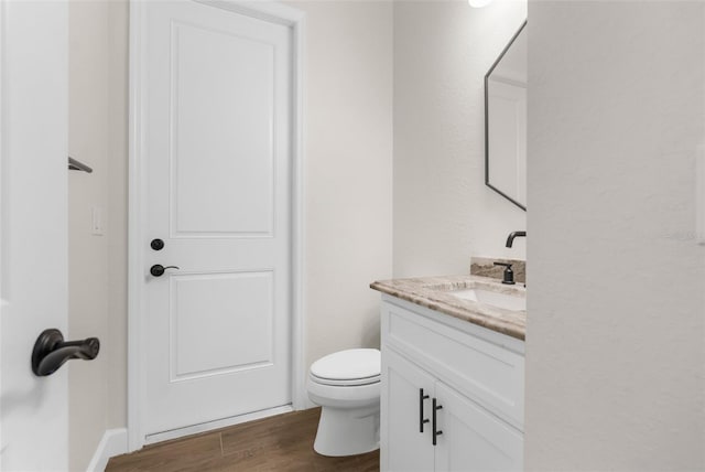 bathroom with hardwood / wood-style floors, vanity, and toilet