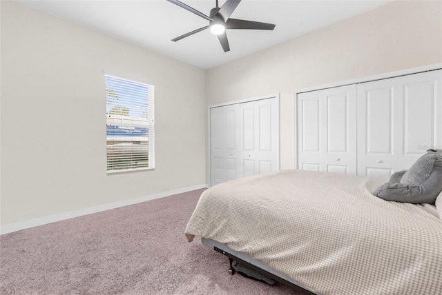 carpeted bedroom featuring multiple closets and ceiling fan