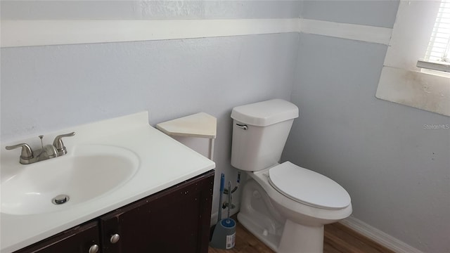 bathroom with wood-type flooring, vanity, and toilet