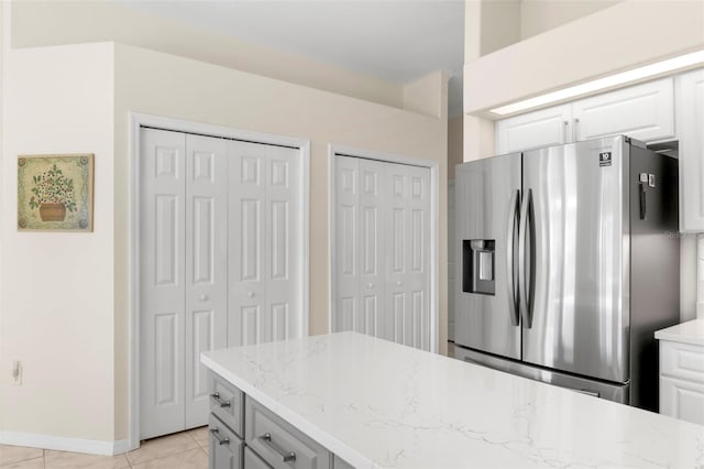 kitchen with white cabinets, stainless steel refrigerator with ice dispenser, light tile patterned floors, and light stone countertops