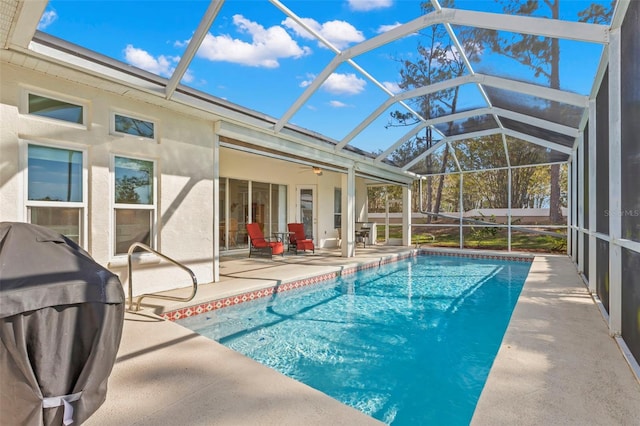 view of swimming pool featuring ceiling fan, grilling area, a patio, and glass enclosure