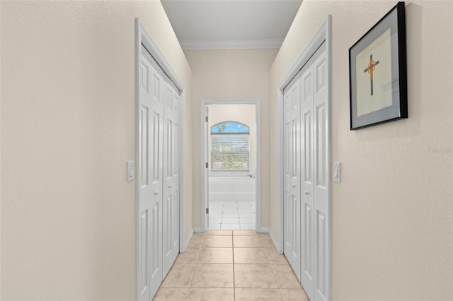 hall with crown molding and light tile patterned floors